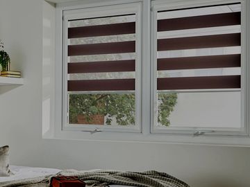 Bedroom window with striped blinds partially open.