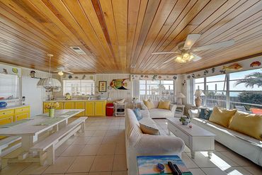 Living and dining space with windows overlooking the sand and emerald water