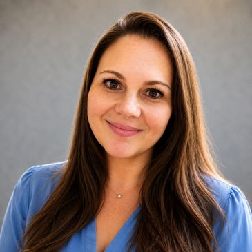 Smiling woman with long brown hair wearing a blue top.