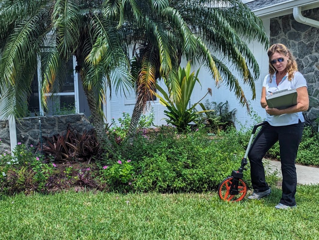 Joann Larkee of Beneficial Landscapes LLC measures and takes notes to prepare a landscape design