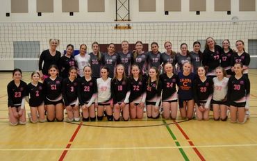 Two volleyball teams posing together on an indoor court.