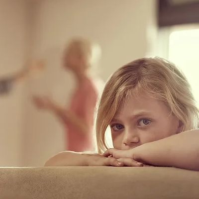 Child sad with parents arguing in background