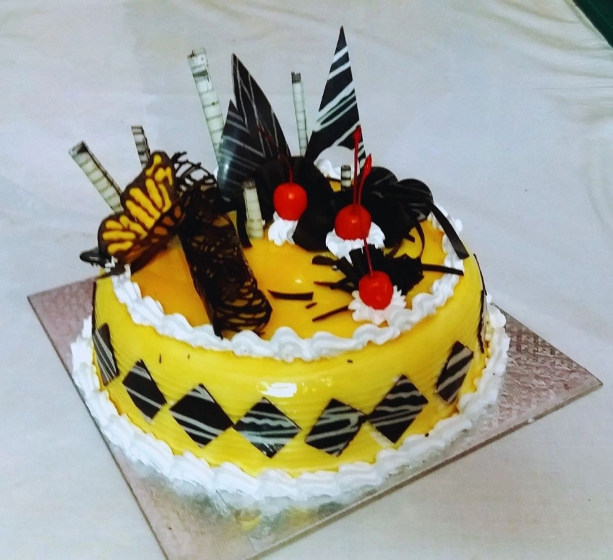 Yellow cake decorated with cherries and chocolate pieces.