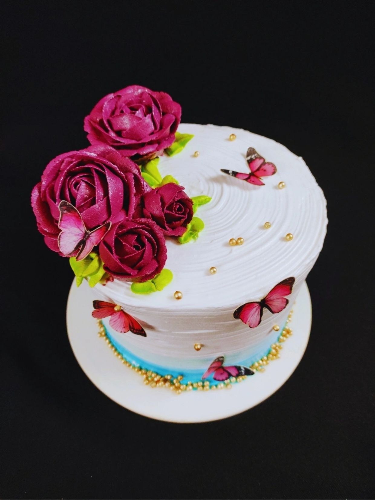 Cake with red roses and pink butterflies decoration.