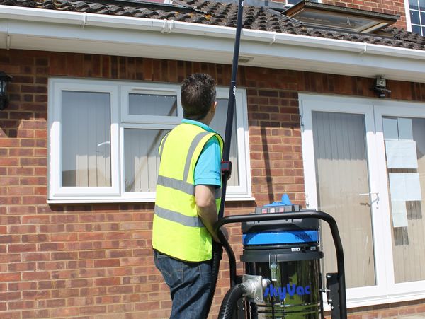 A professional cleaning the gutters of a house