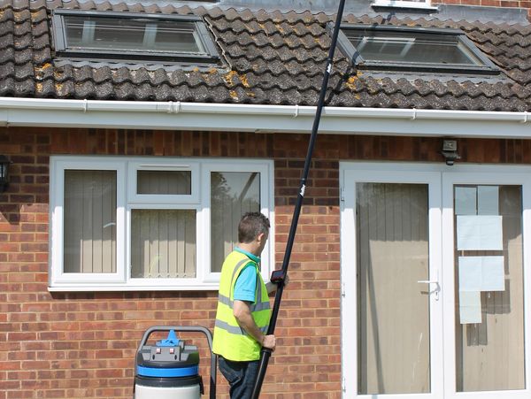 A professional cleaning the gutters of a house