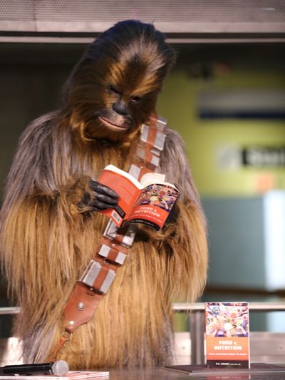 Chewbacca reading Food and Nutrition: What Everyone Needs to Know by Dr. P.K. Newby.