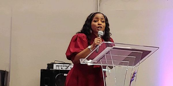 Dara speaking in a red dress at an event 