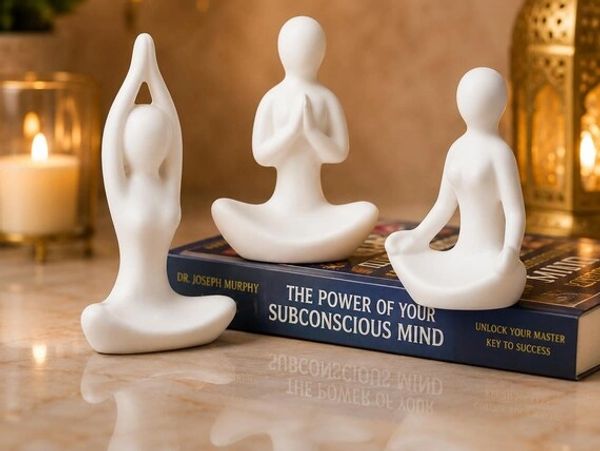 Three white yoga figurines on a book about subconscious mind.