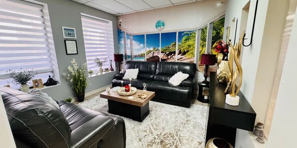 Modern living room with black leather sofas and tropical wall mural.