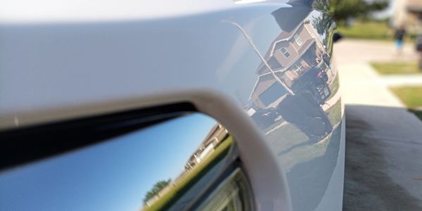 Close-up of a shiny car surface reflecting a neighborhood.
