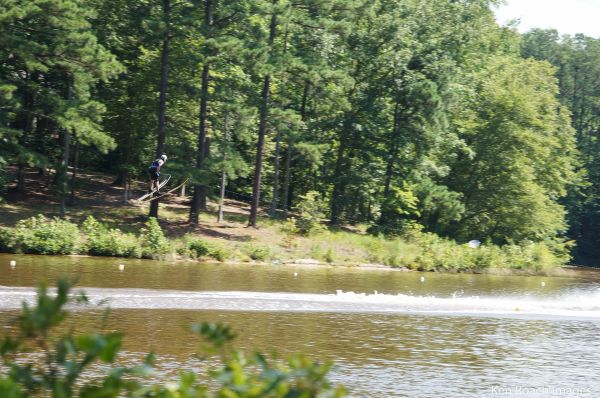 Person water skiing on a lake surrounded by trees.