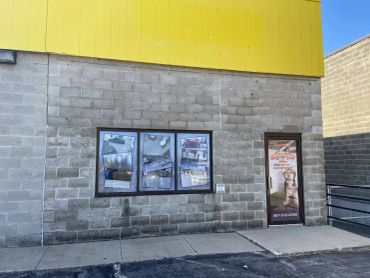 Storefront with yellow top, window displays, and a door with a promotional graphic.