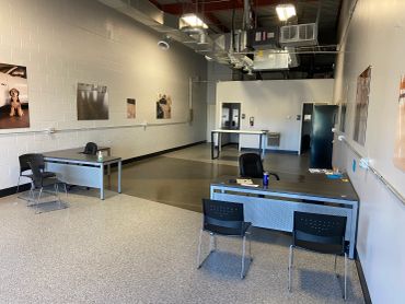 A spacious room with desks, chairs, and wall art in an industrial-style setting.