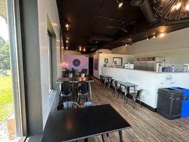 Empty modern cafe with black tables and chairs.