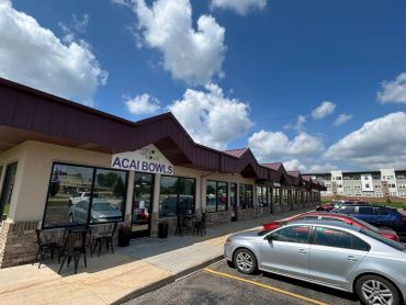 Strip mall with Acai Bowls store under a blue sky.
