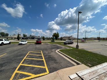 Empty parking lot with a few cars and blue sky.