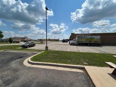 Large parking lot with few vehicles under a partly cloudy sky.