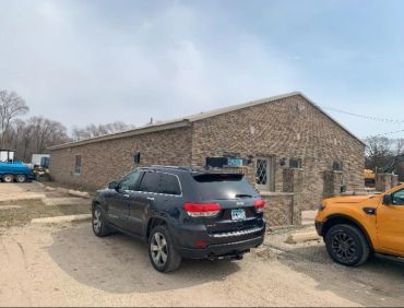 A black SUV parked near a brown brick building under a cloudy sky.