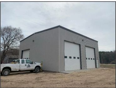 Metal garage with three large doors and a white pickup truck.