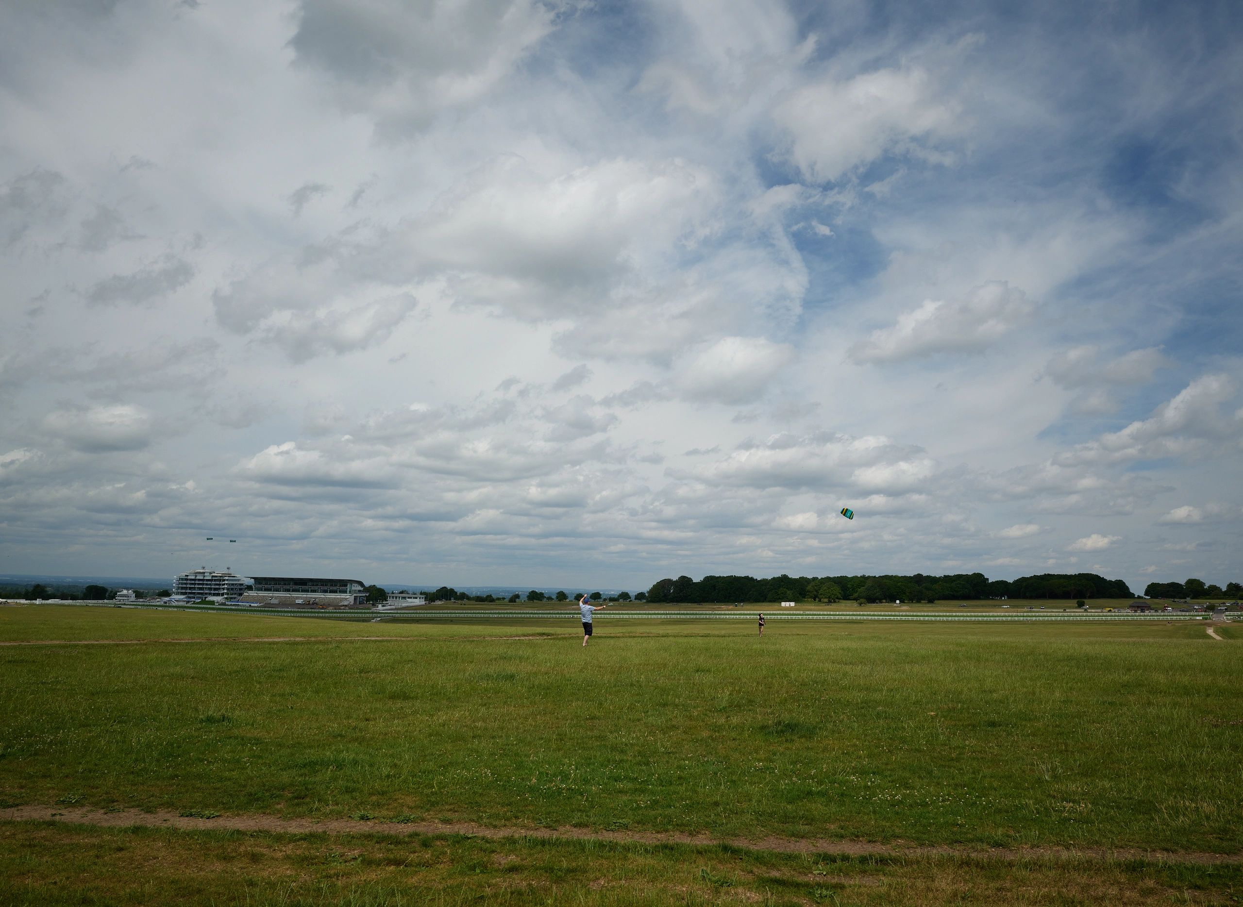 People flying a kite on a cloudy day in a large open field.