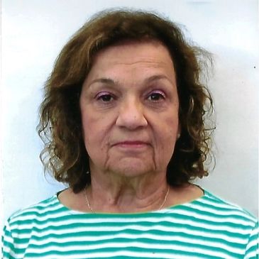 Older woman in striped shirt with neutral expression.