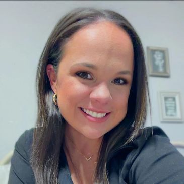 Smiling woman with dark hair and gold hoop earrings.