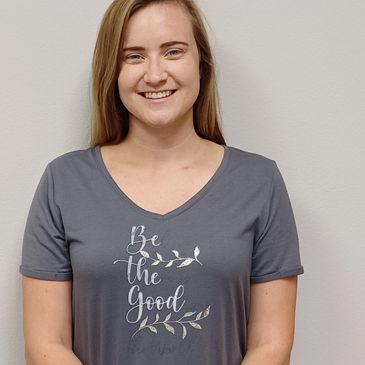 Smiling woman in a gray shirt with motivational text.