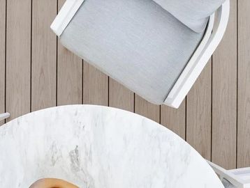 Top view of a gray cushioned chair and round marble table.