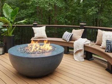 Outdoor fire pit with curved seating on a wooden deck.
