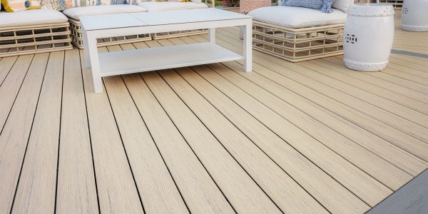 Modern outdoor patio with beige wooden deck and white furniture.