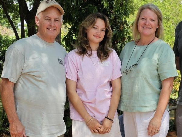 Three people smiling outdoors in casual clothes.