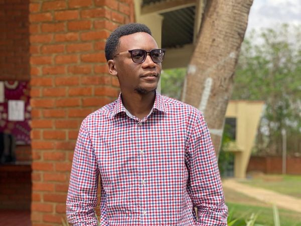 Man wearing sunglasses and a checkered shirt outdoors.