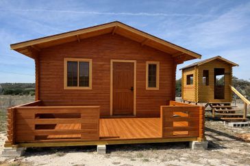 Small wooden cabin with a porch under a clear sky.