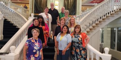 Group of people posing on a grand staircase inside a building.