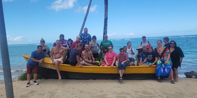 Group of people posing on a yellow boat by the beach.