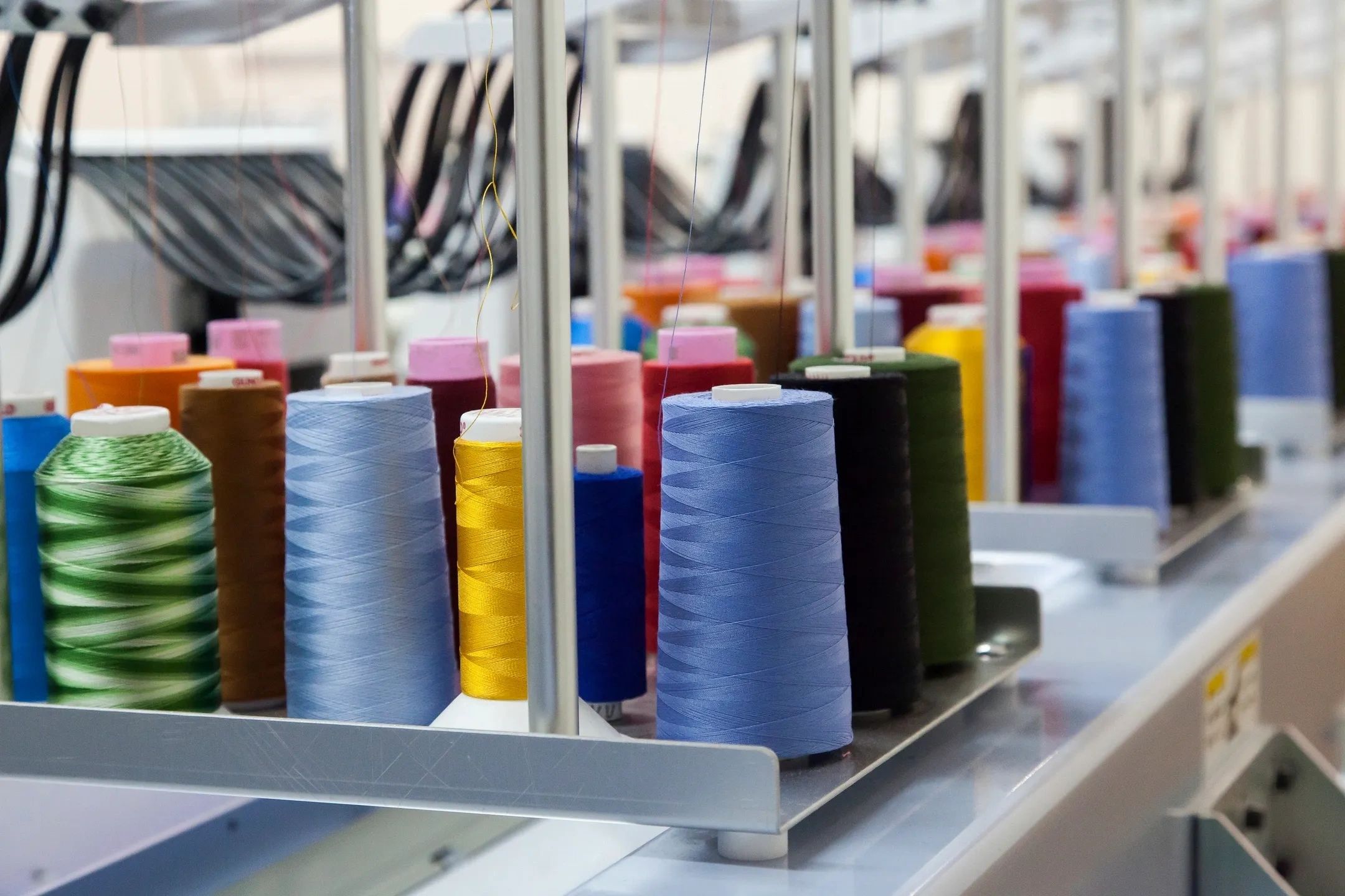 Colorful spools of thread lined up on a sewing machine rack.