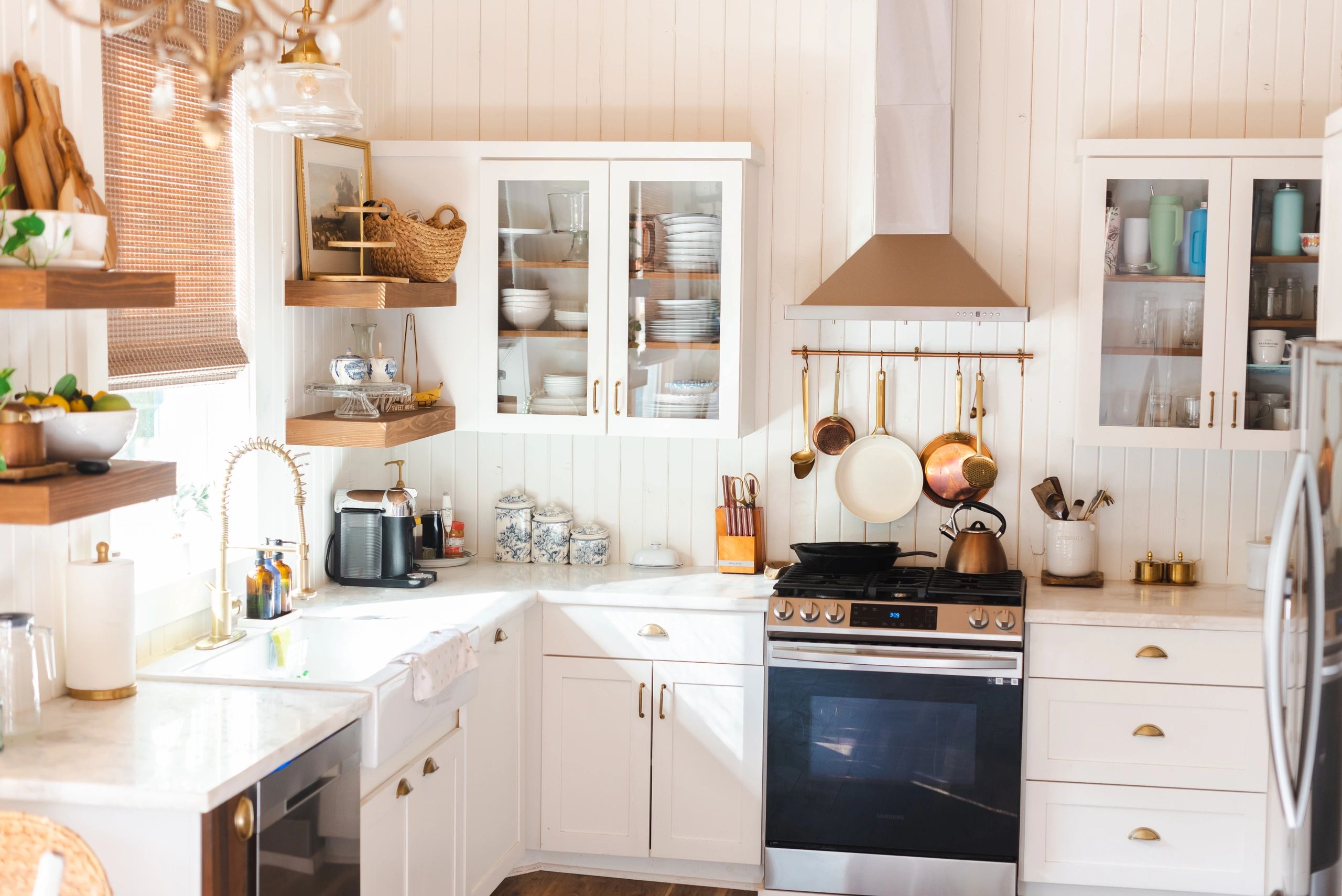 Cozy kitchen with white cabinets, wooden shelves, and brass accents.