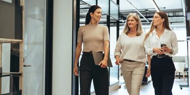 Three professional women walking and talking in a modern office.