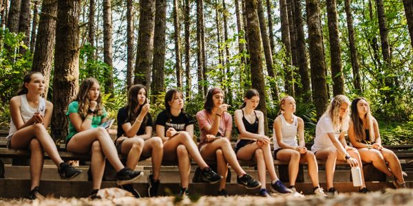 High school girls cross country runners talking in the woods