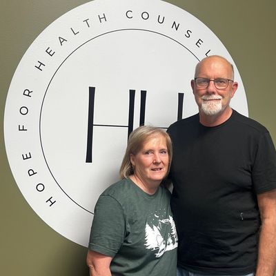 Two people standing in front of a health counseling sign.