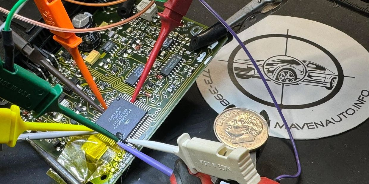 Close-up of electronic circuit board with multiple colored probes attached.