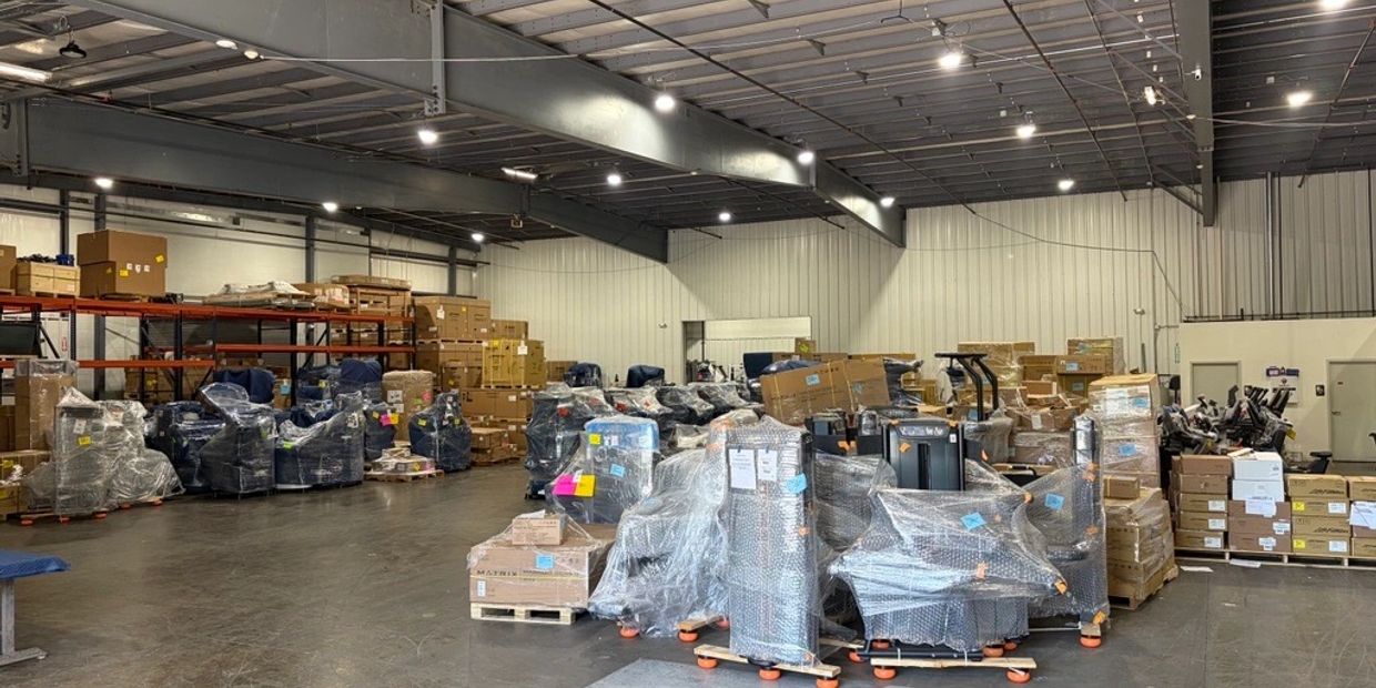 Warehouse storing wrapped gym equipment and stacked cardboard boxes.