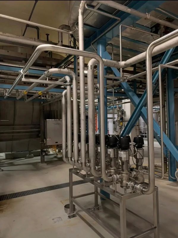 Industrial stainless steel pipes and valves in a factory setting.