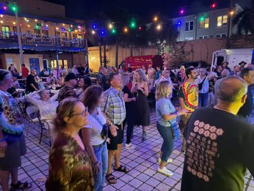 People enjoying a nighttime outdoor event under colorful string lights.