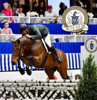 Equestrian rider and horse mid-jump during a competition at Pin Oak Charity Horse Show.