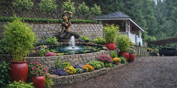 Serene garden pond with a mermaid statue fountain surrounded by vibrant flowers and greenery.