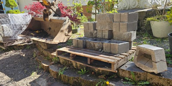 Construction site with stacked concrete blocks and an excavator bucket.