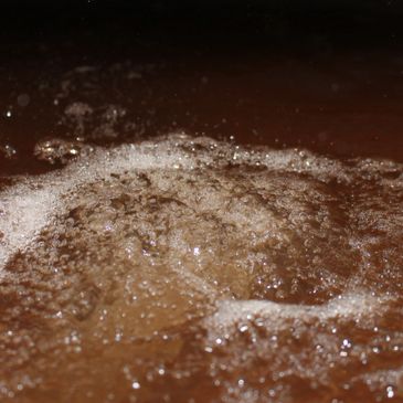 Close-up of bubbles forming on the surface of brown liquid.