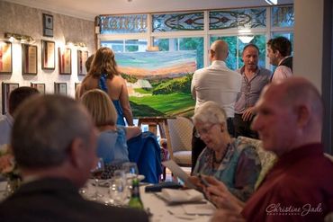 Guests enjoy watching  Artist Donna Gibb instruct guests to add a brushstroke to the  wedding painti